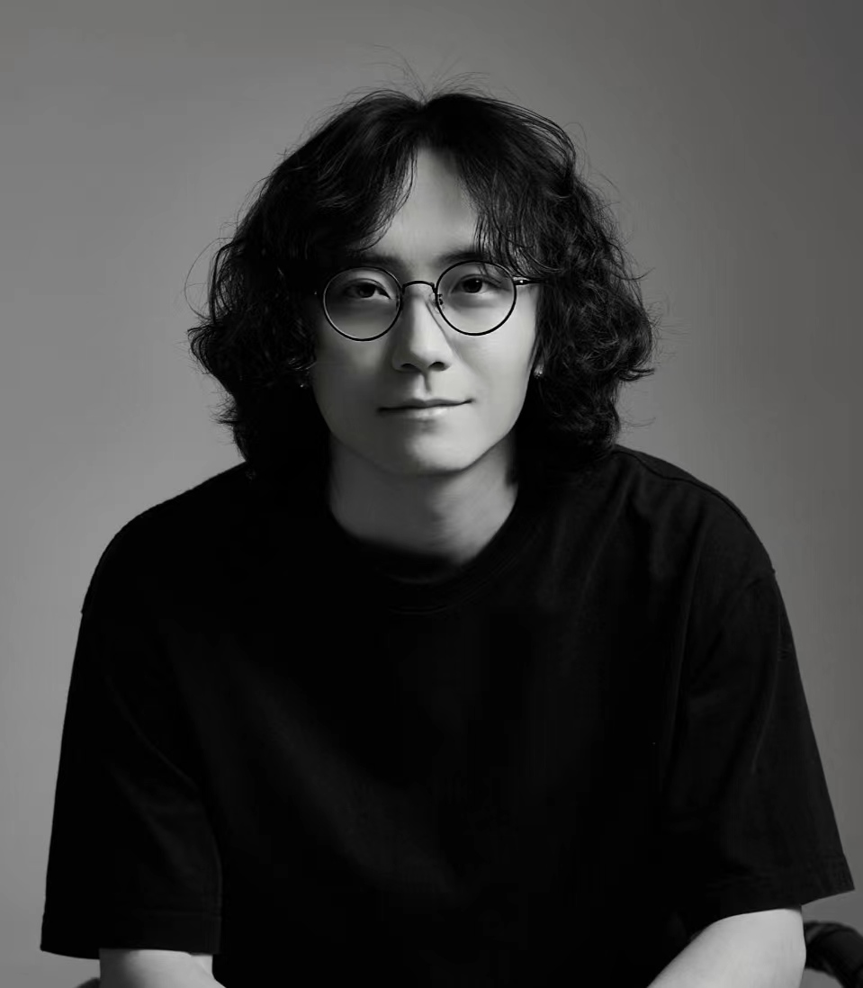张志伟 Evan Jahng 的黑白肖像,戴着圆框眼镜,身穿黑色上衣
